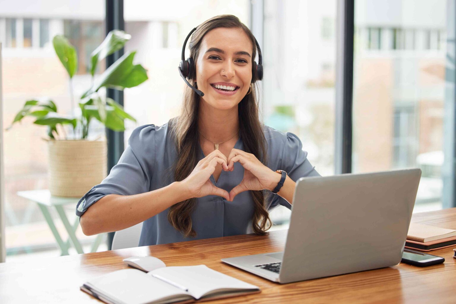 Woman making heart hands at desk